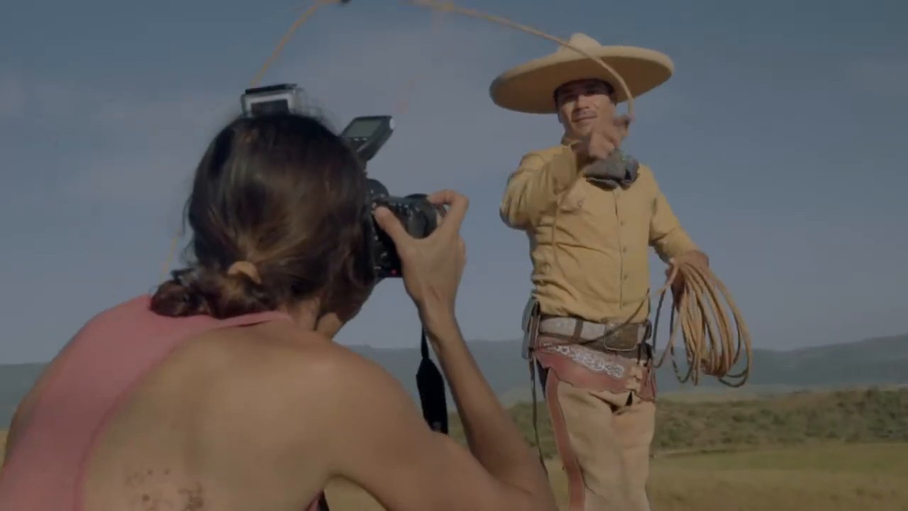 Photographer with a camera photographing a charro holding a lasso in a field near Compostela, Mexico