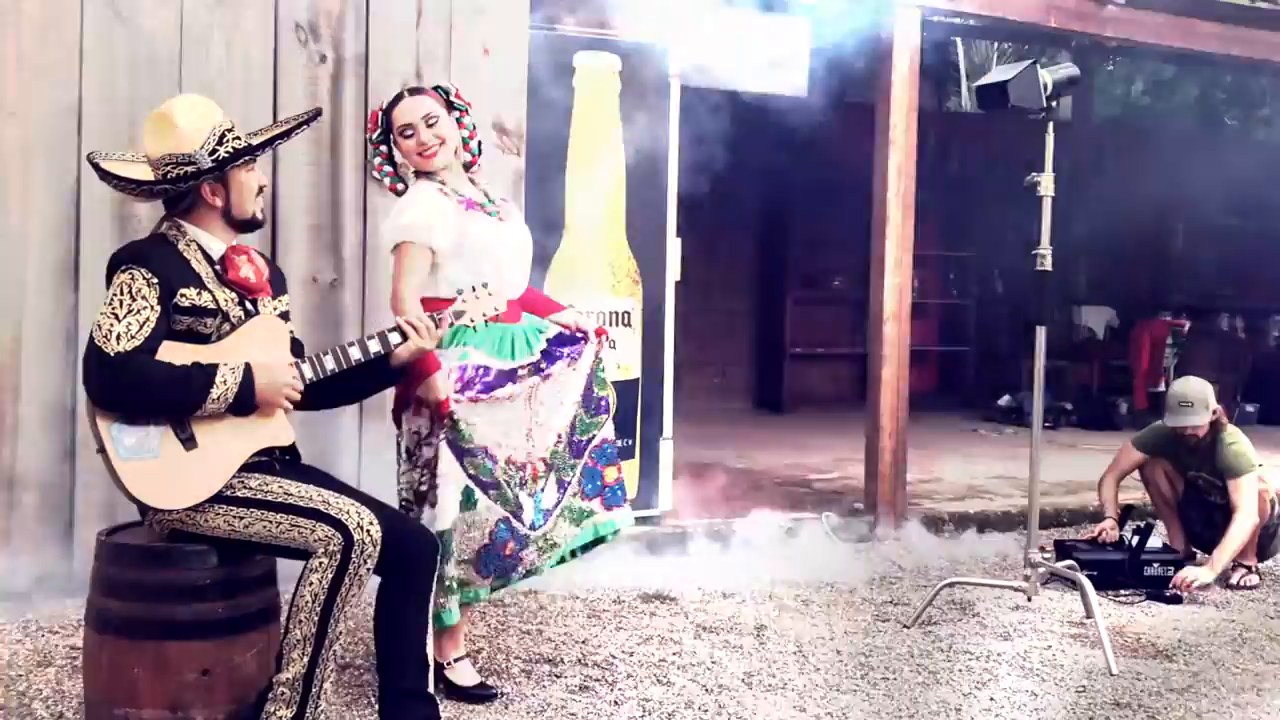 Mariachi with a guitar posing beside a folklorico dancer in a China Poblana dress, with a light stand on set in Sayulita, Nayarit